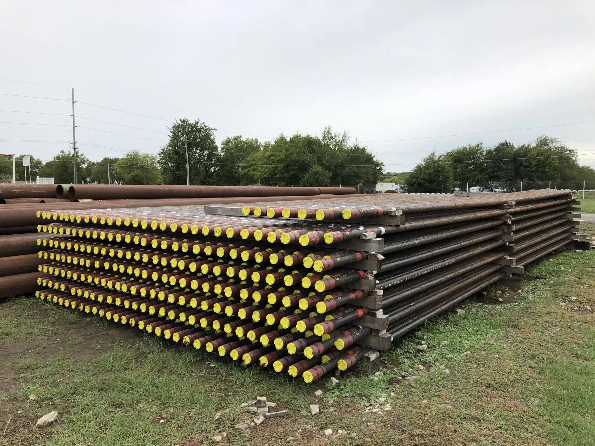 Racks of steel pipe with yellow thread protectors in the Reddy Pipe & Supply yard in Tulsa